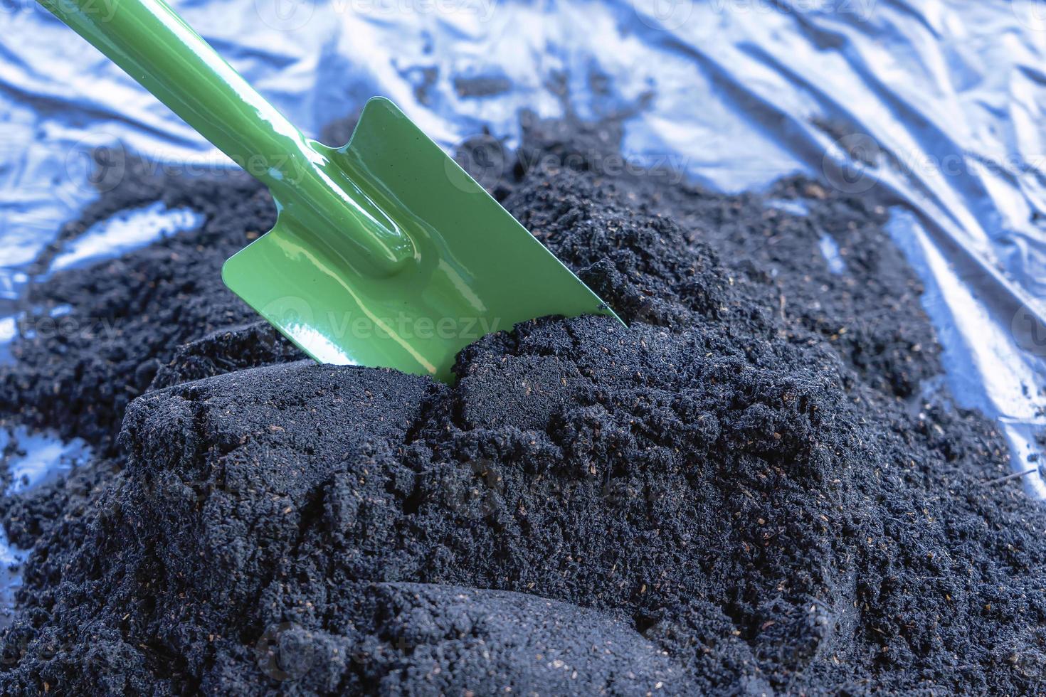 Preparation of soil mixture from fertile compost, humus and vermiculite on  black garbage bag floor in garden. Mixing the soil components for the preparation of the substrate for transplanting plants. photo