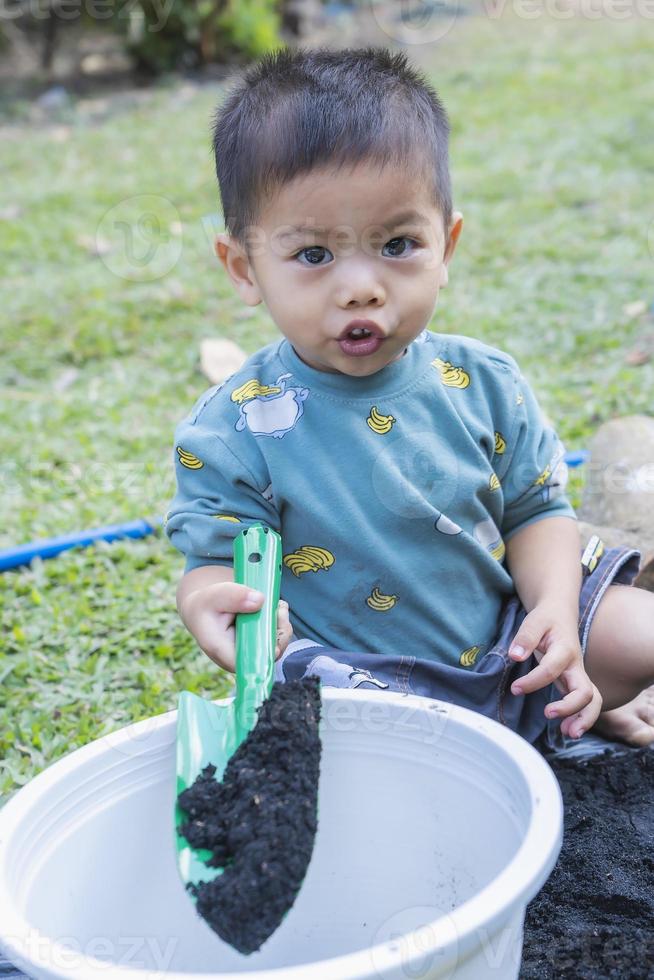 niño pequeño palea tierra en macetas para preparar plantas para plantar. niño pequeño cavando tierra para plantar para el pequeño ayudante de la madre. jardinería. pasatiempos en casa horticultura. concepto de actividades de ocio foto