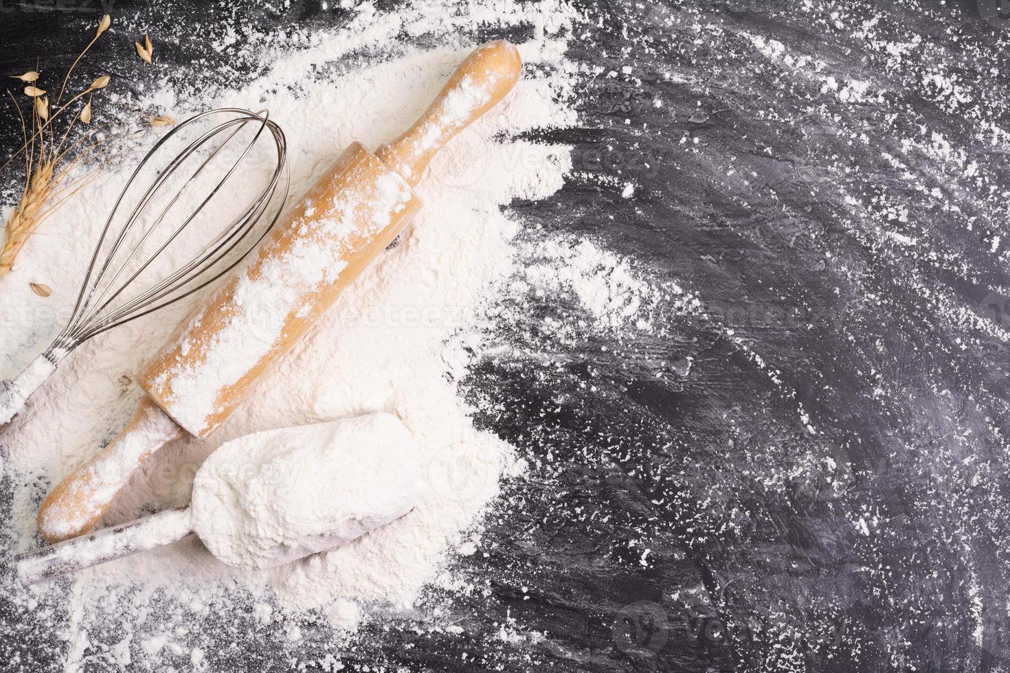 Heaps of wheat flour with ears of wheat on the table, black background - top view photo