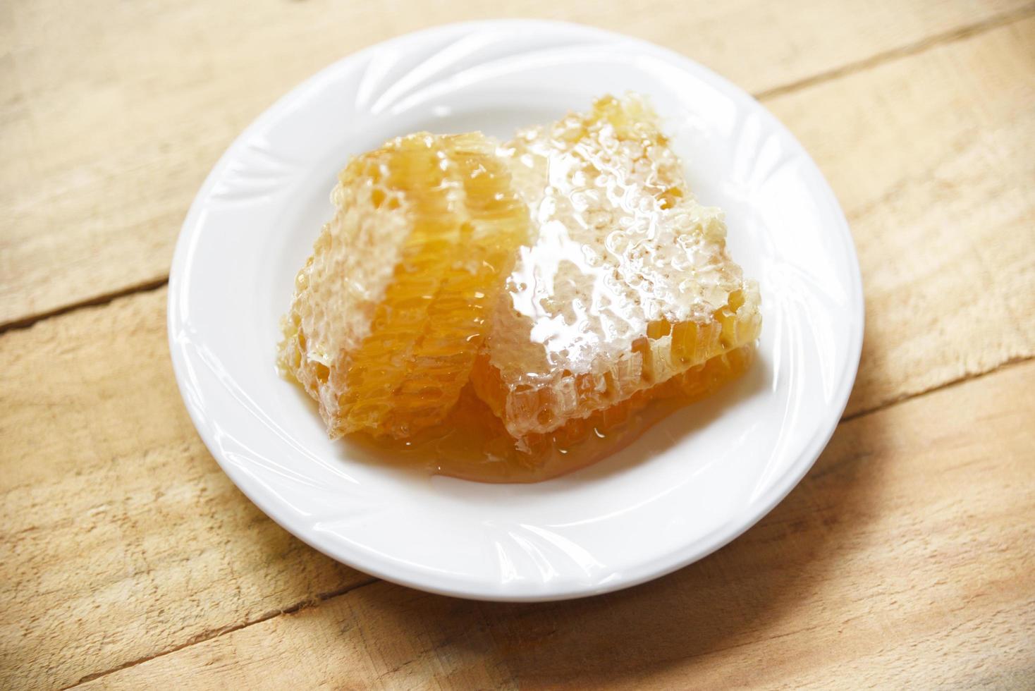 Fresh honey - Close up of yellow sweet honeycomb slice on white plate natural healthy food photo