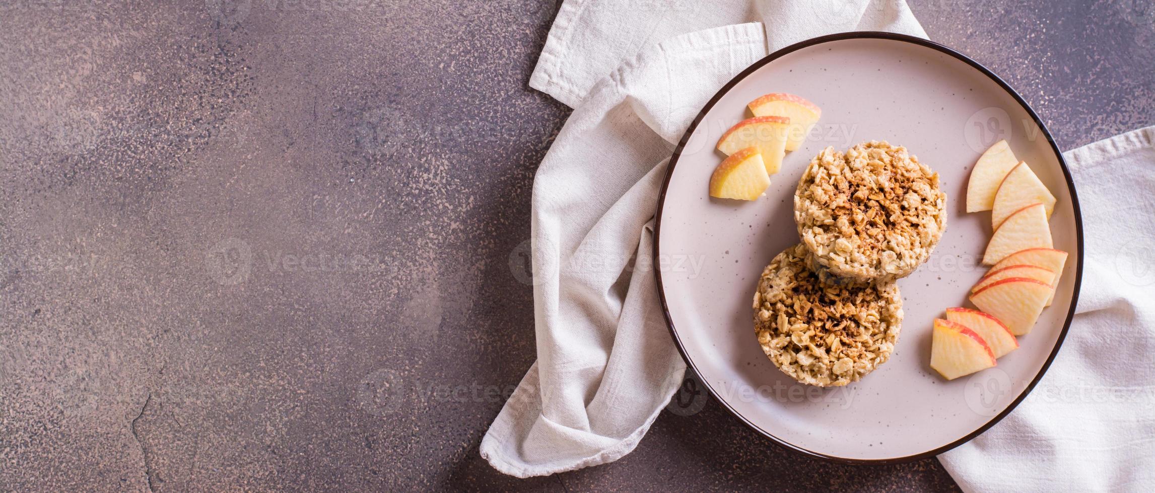 Appetizing crumble of apples and oatmeal on a plate and fruits on the table. Top view web banner photo