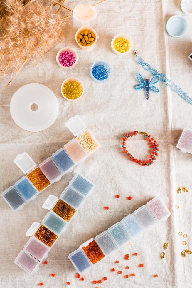 Items for beading - boxes with beads, thread and scissors on the table. Creative leisure, home teaching crafts for children. Top  and vertical view. photo