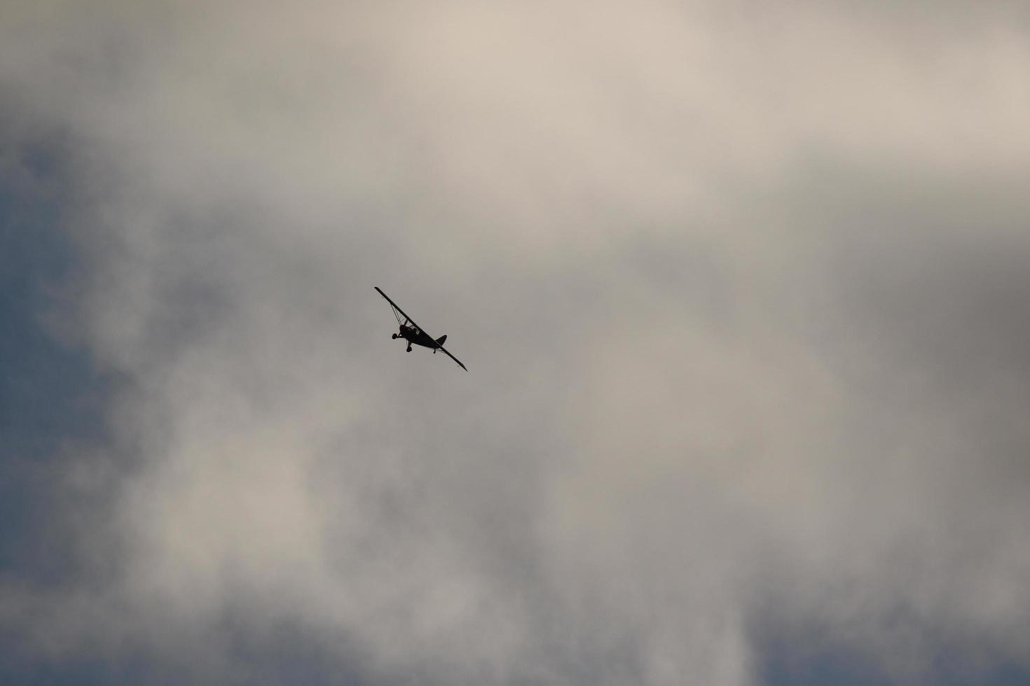 pequeño avión volador en el cielo en contra oscuro nubes foto