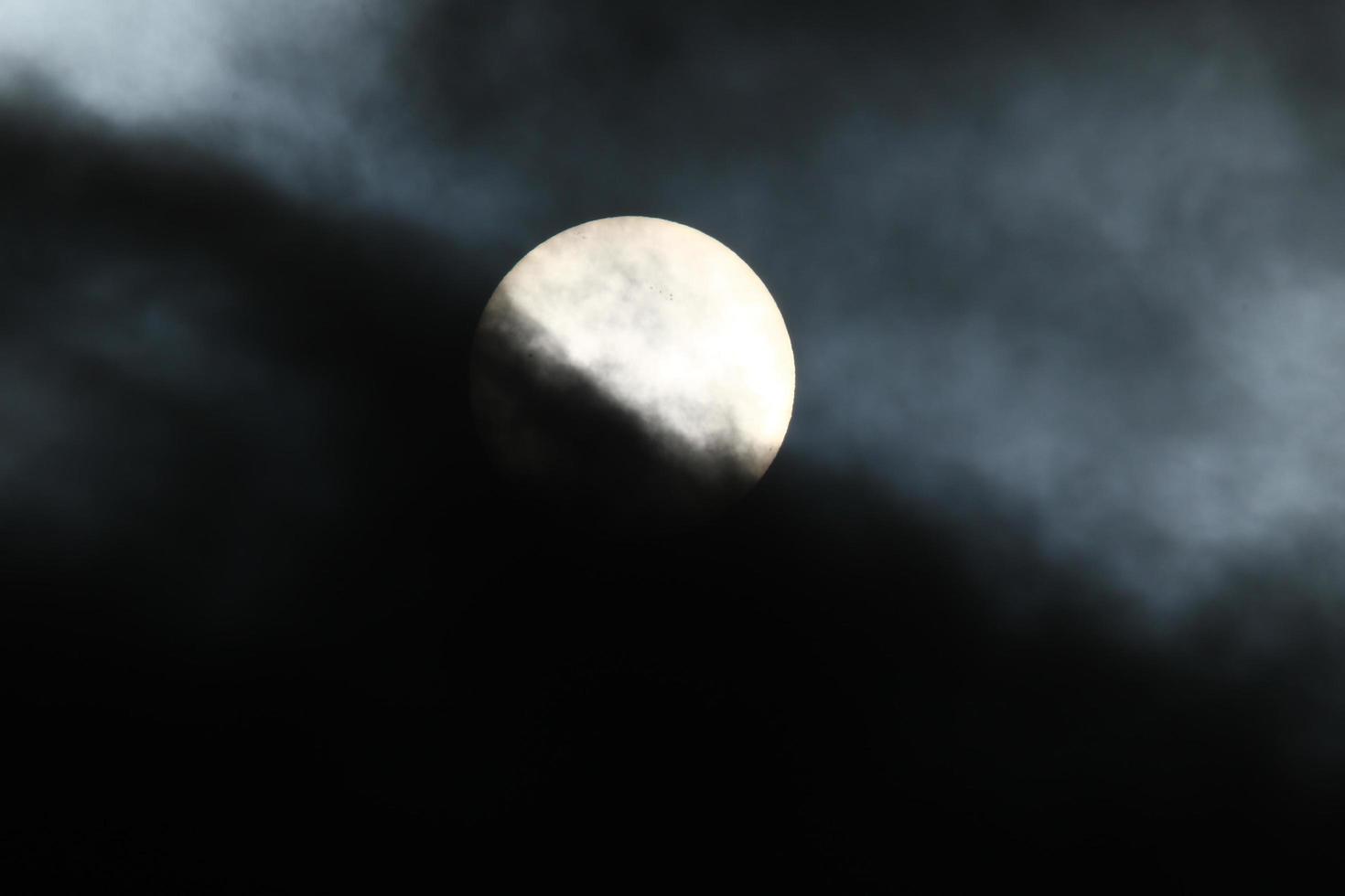 Sun disk behind backlit clouds photo