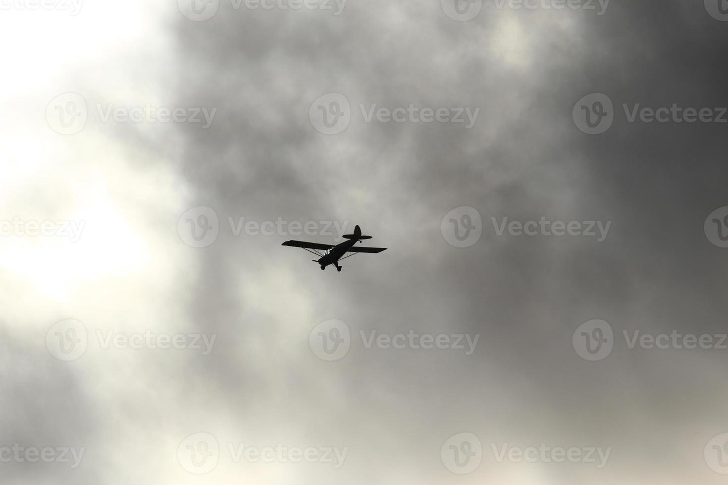 Small plane flying in the sky against dark clouds photo