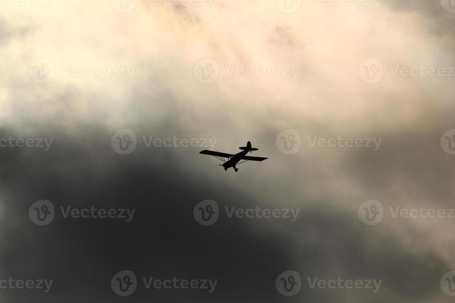 Small plane flying in the sky against dark clouds photo