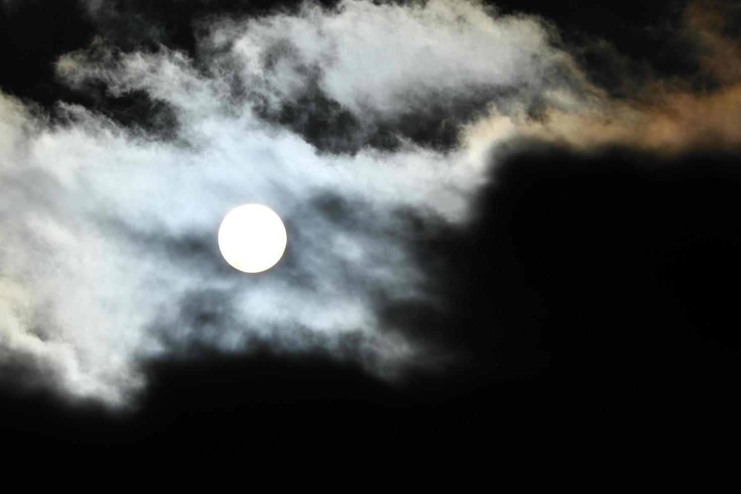 Sun disk behind backlit clouds photo