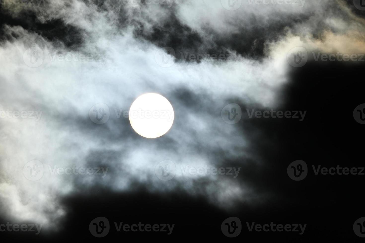 Sun disk behind backlit clouds photo