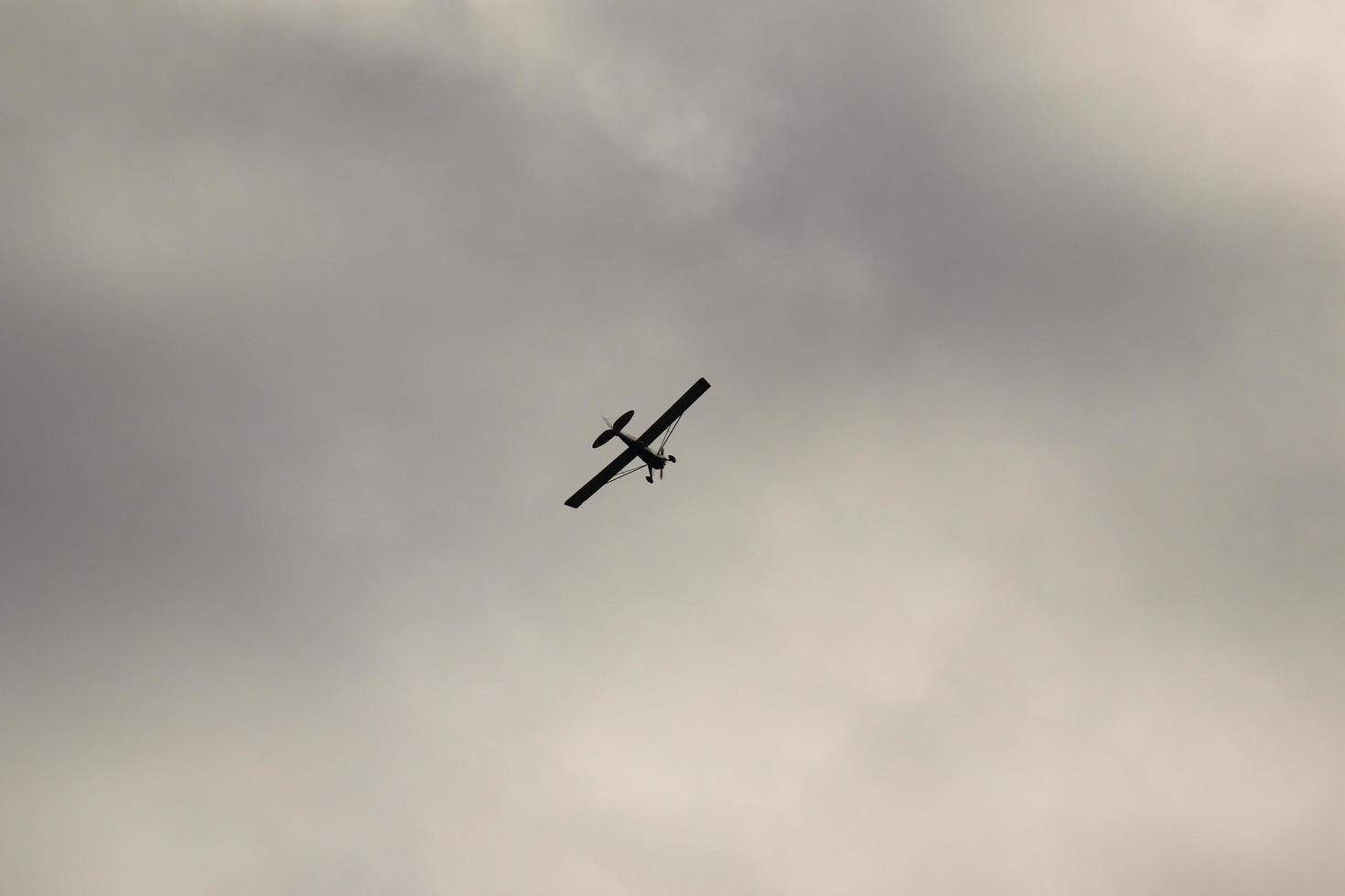 pequeño avión volador en el cielo en contra oscuro nubes foto