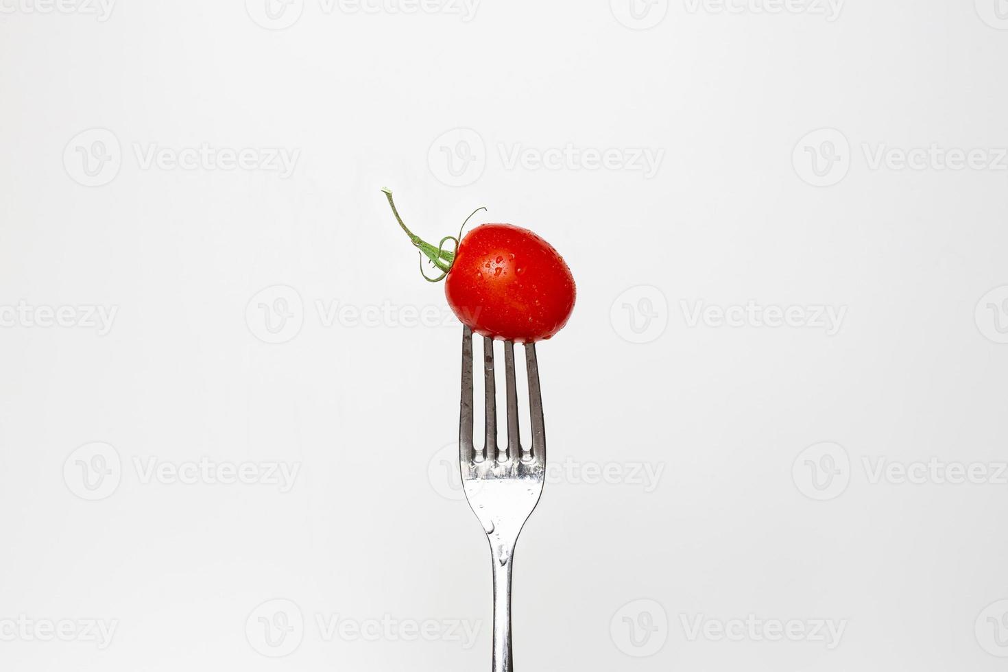 Photo of a fresh cherry tomato on a fork isolated on a white background, part of a series.