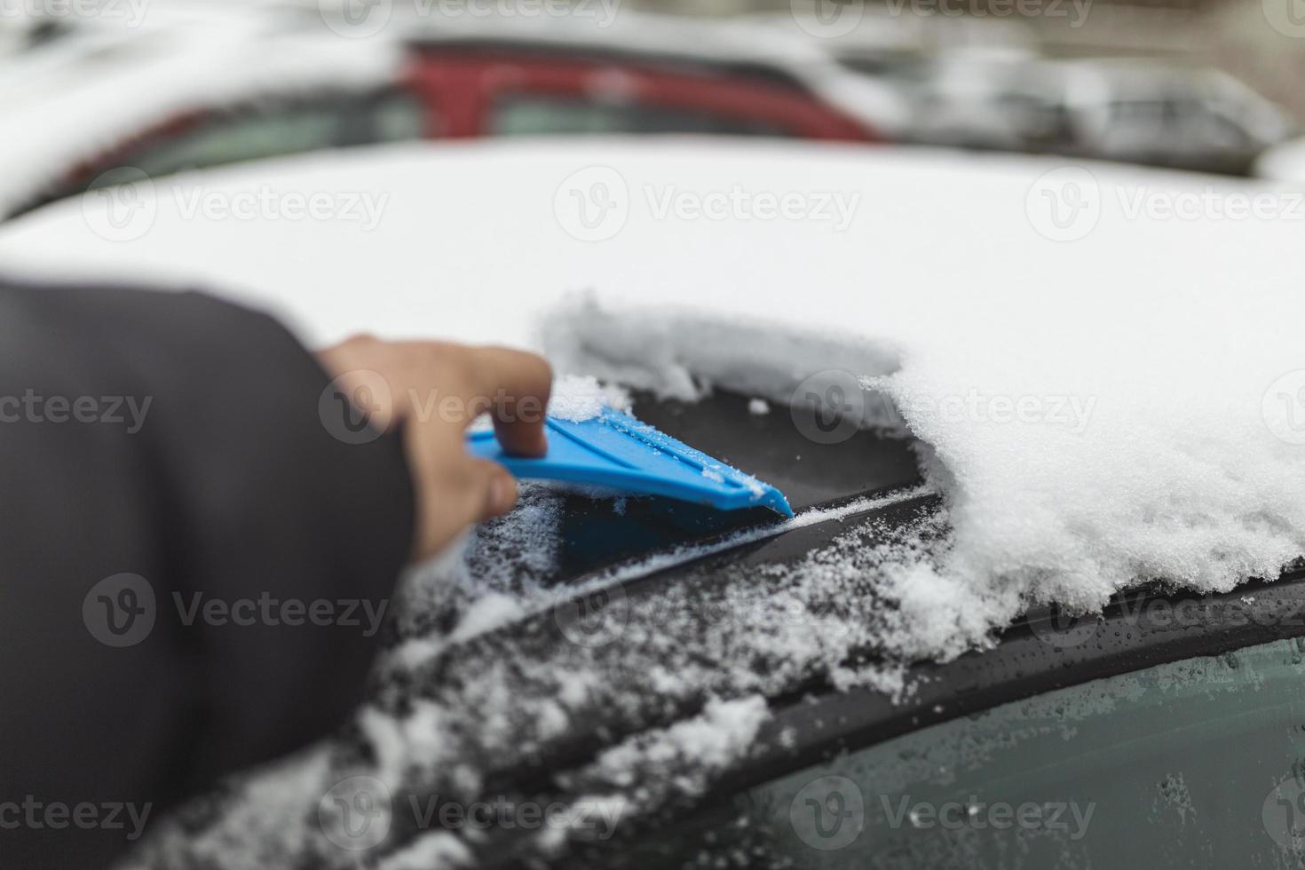 Transportation, winter, weather, people and vehicle concept - man cleaning snow from car with brush photo