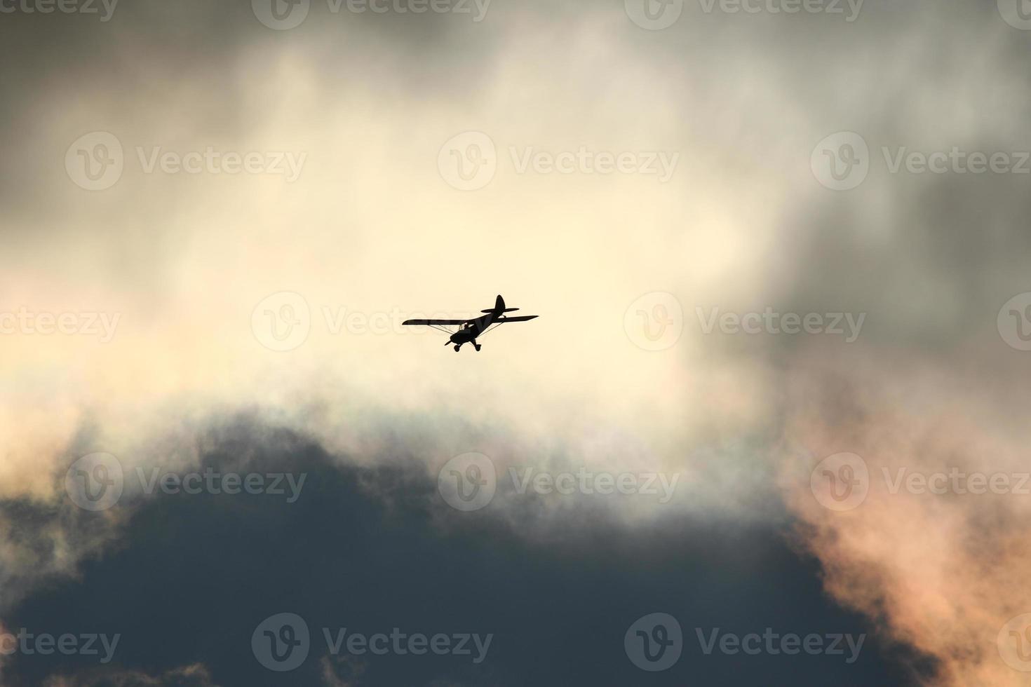 Small plane flying in the sky against dark clouds photo