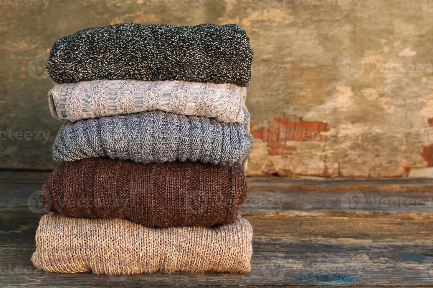 Pile of colorful warm clothes on wooden background. photo