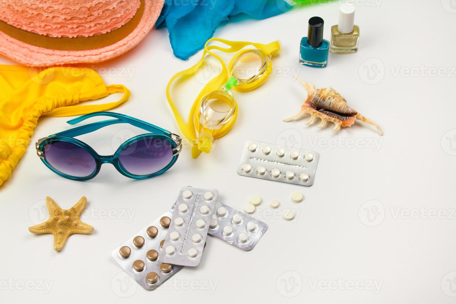 Summer womens beach accessories for your sea holiday and pill on white background. Concept of medication required in journey. Top view. Flat lay. photo