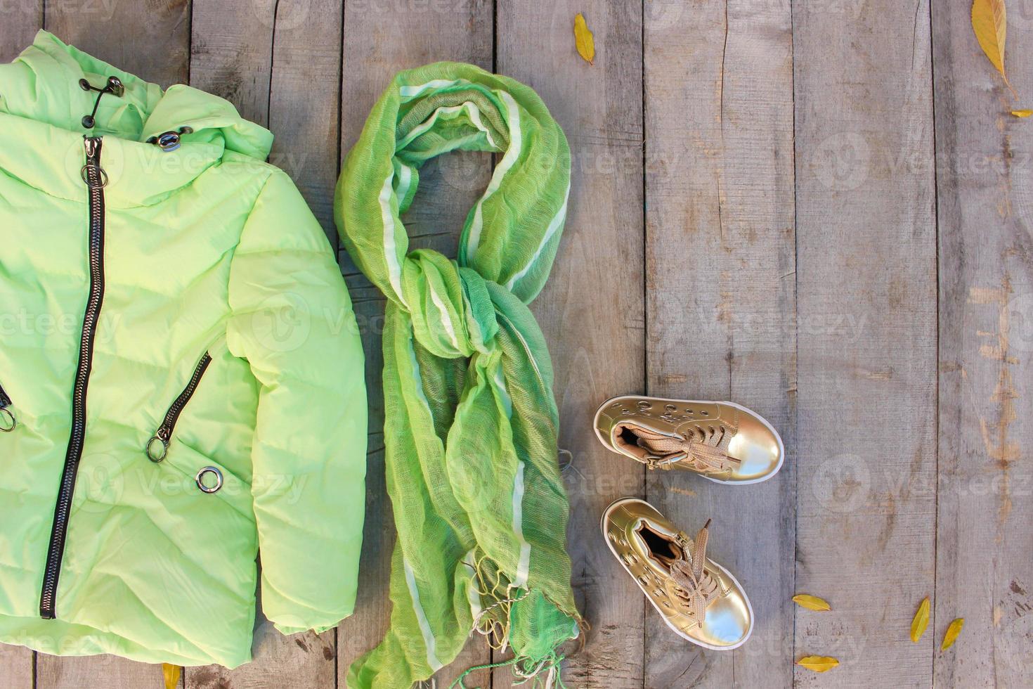 Children's autumn clothes and yellow leaves on old wooden background. Top view. Flat lay. photo