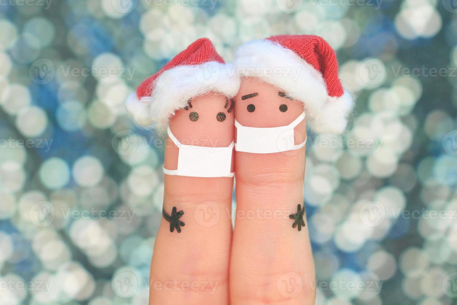 Fingers art of couple in medical mask from COVID-2019 celebrates Christmas. Concept of people in New Year hats. Toned image. photo