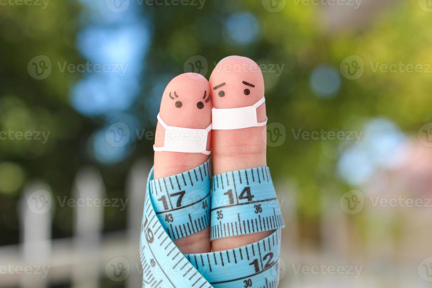 Fingers art of happy couple with tape measure. Concept of sports people in medical mask from COVID-2019. photo