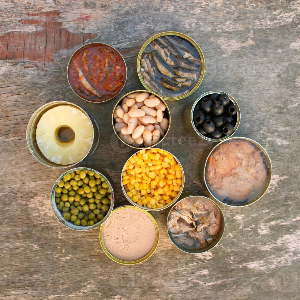 Different open canned food on old wooden background. Top view. Flat lay. photo