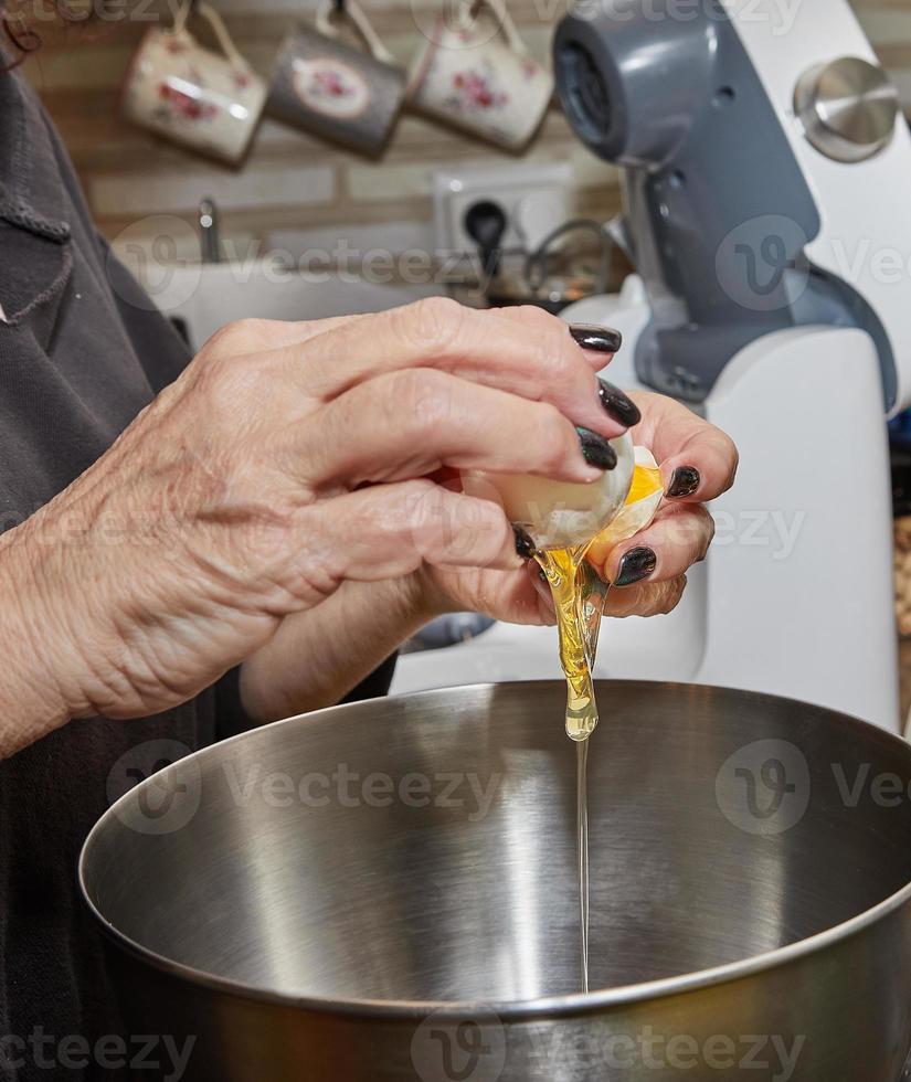 Chef cracks an egg into dish that is being prepared in bowl photo