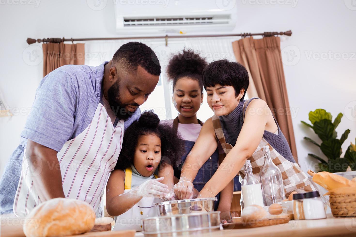 Happy African American family enjoy together while prepare the flour for making cookies at home photo