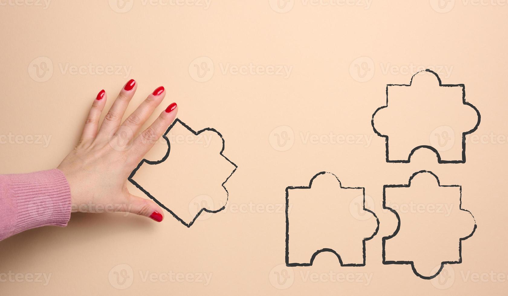 Female hand and drawn puzzle elements on a beige background, concept of finding solutions photo