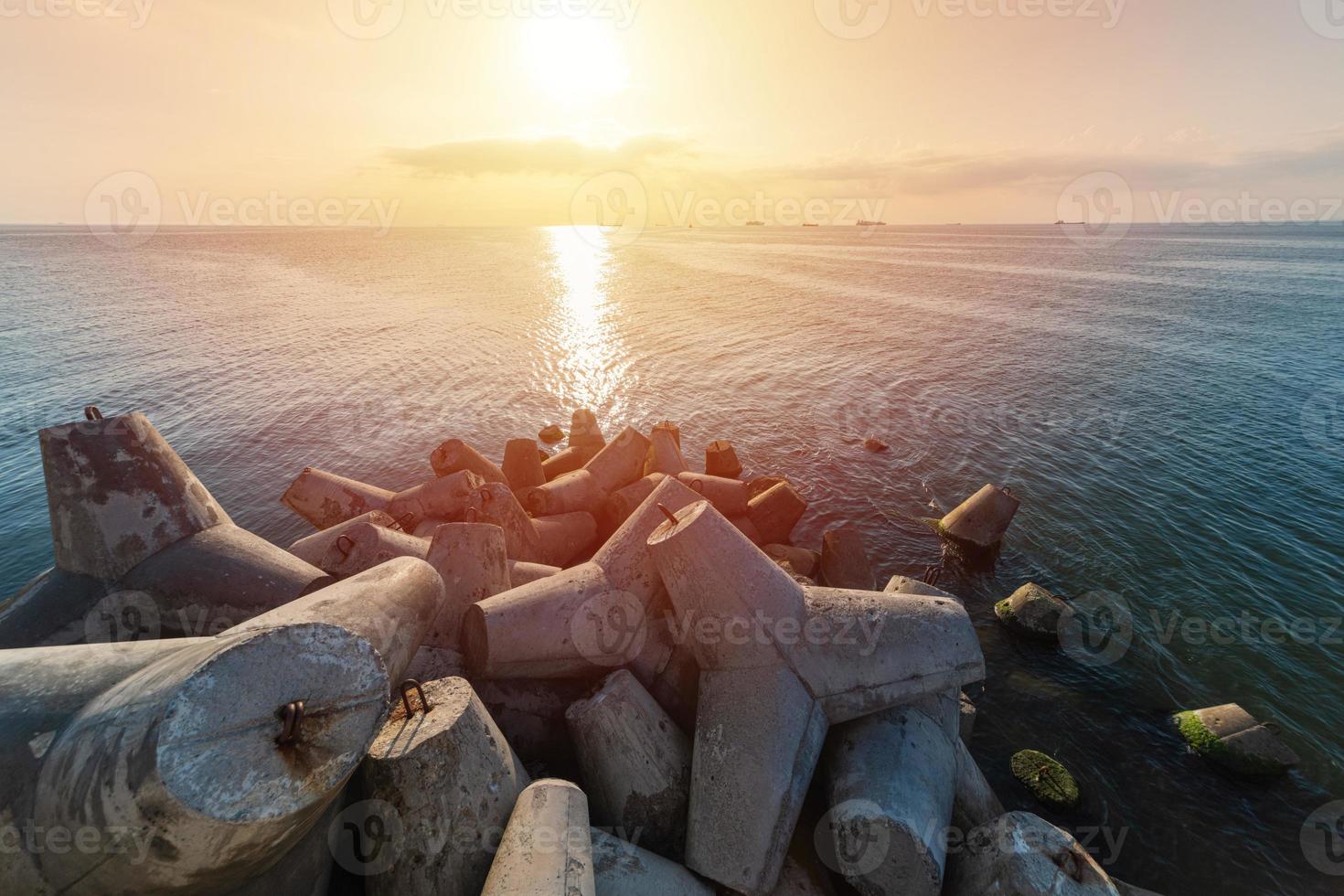 hermoso paisaje marino al atardecer. rompeolas tetrápodos en tierra del muelle. buques de carga en el horizonte. sueños de viaje y motivación foto