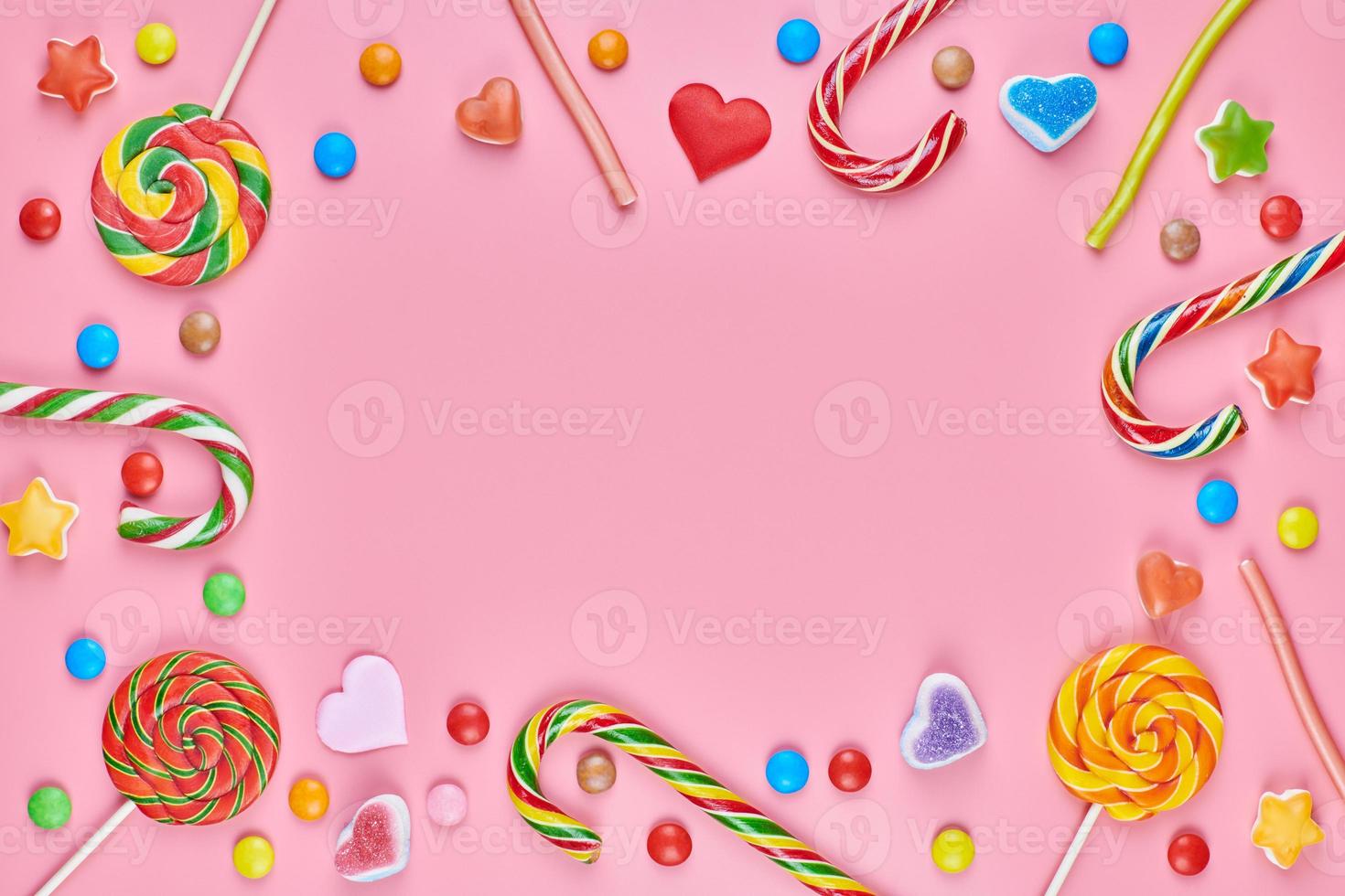 Sweet candy copy space frame with lollipops on pink background photo
