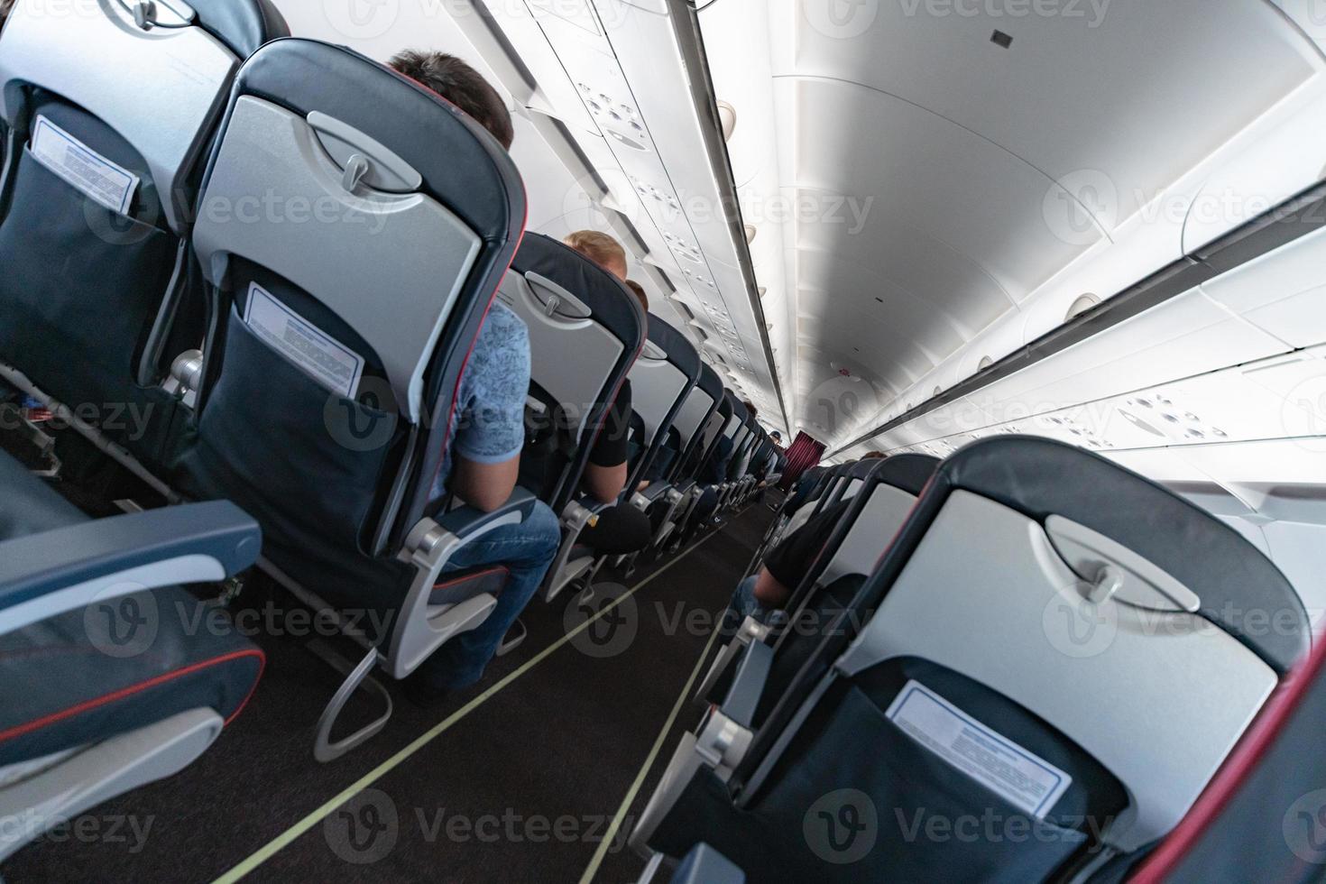 Airplane cabin seats with passengers. Economy class of new cheapest low-cost airlines. Travel trip to another country. Turbulence in flight. photo