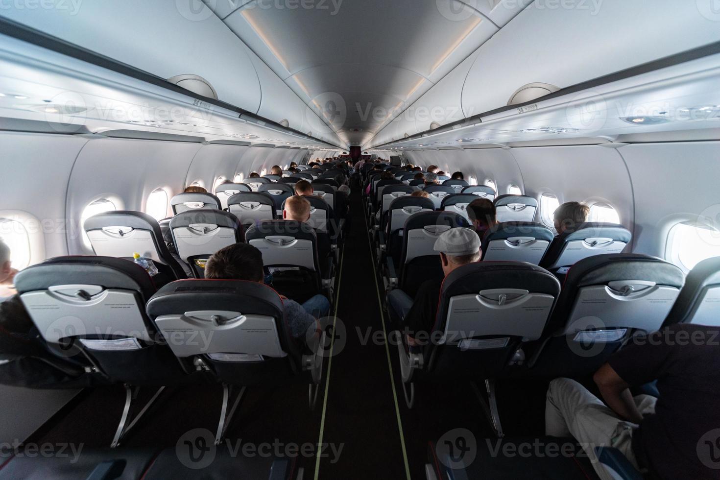 Airplane cabin seats with passengers. Economy class of new cheapest low-cost airlines without delay or cancellation of flight. Travel trip to another country. photo