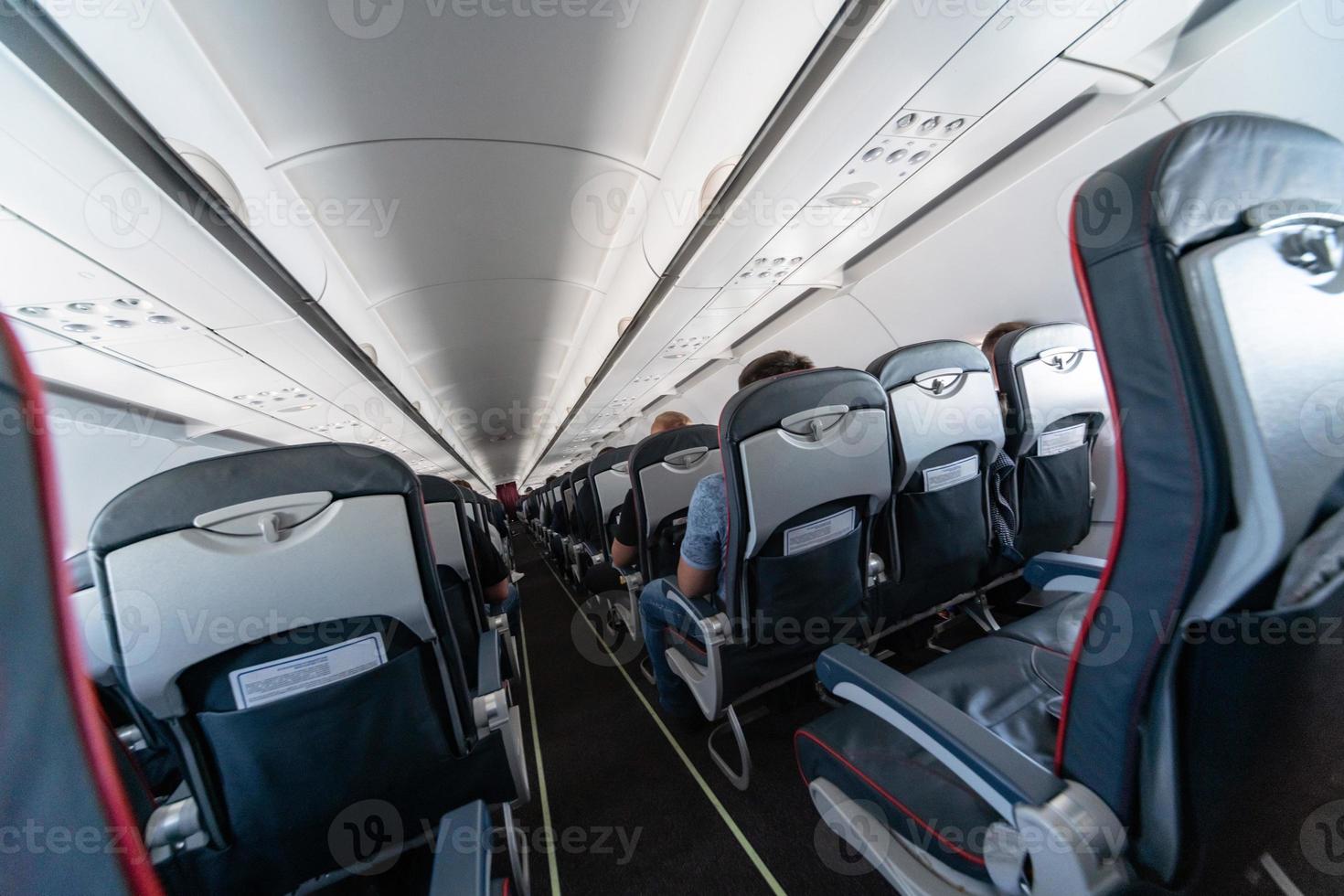 Airplane cabin seats with passengers. Economy class of new cheapest low-cost airlines. Travel trip to another country. Turbulence in flight. photo