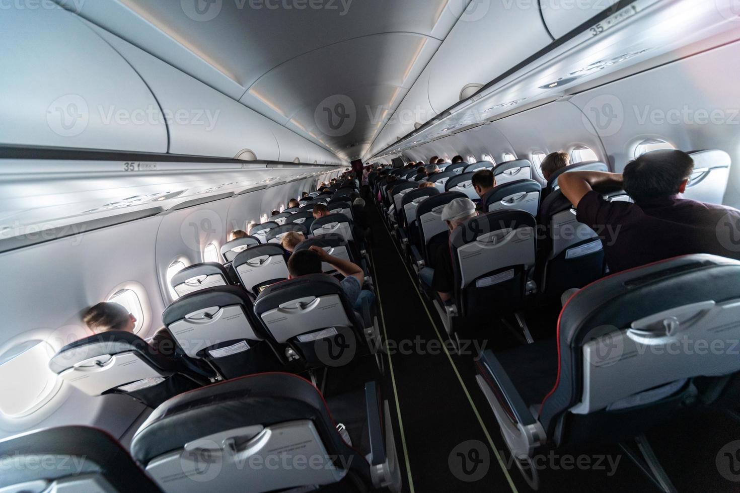 Airplane cabin seats with passengers. Economy class of new cheapest low-cost airlines. Travel trip to another country. Turbulence in flight. photo