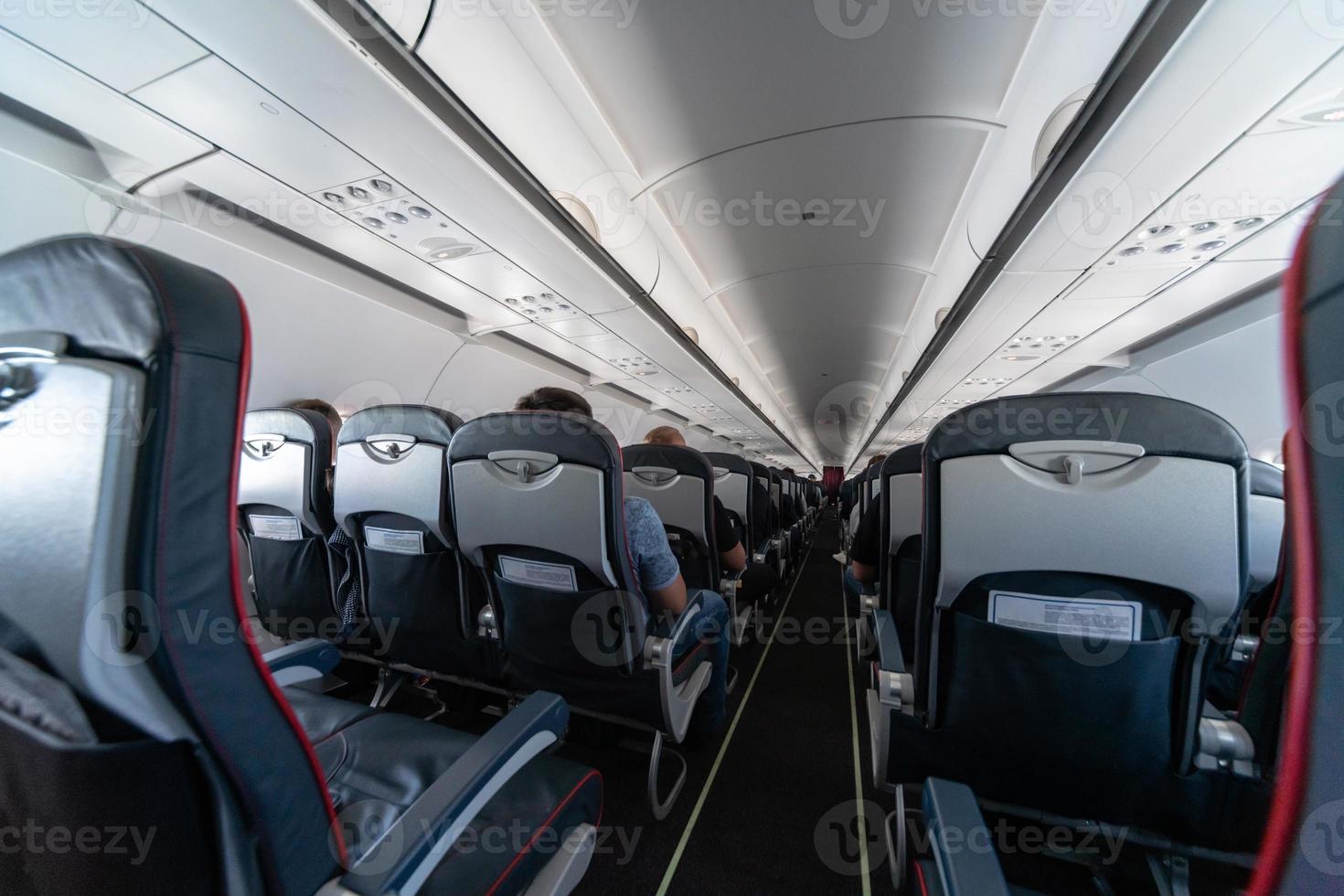 Airplane cabin seats with passengers. Economy class of new cheapest low-cost airlines. Travel trip to another country. Turbulence in flight. photo