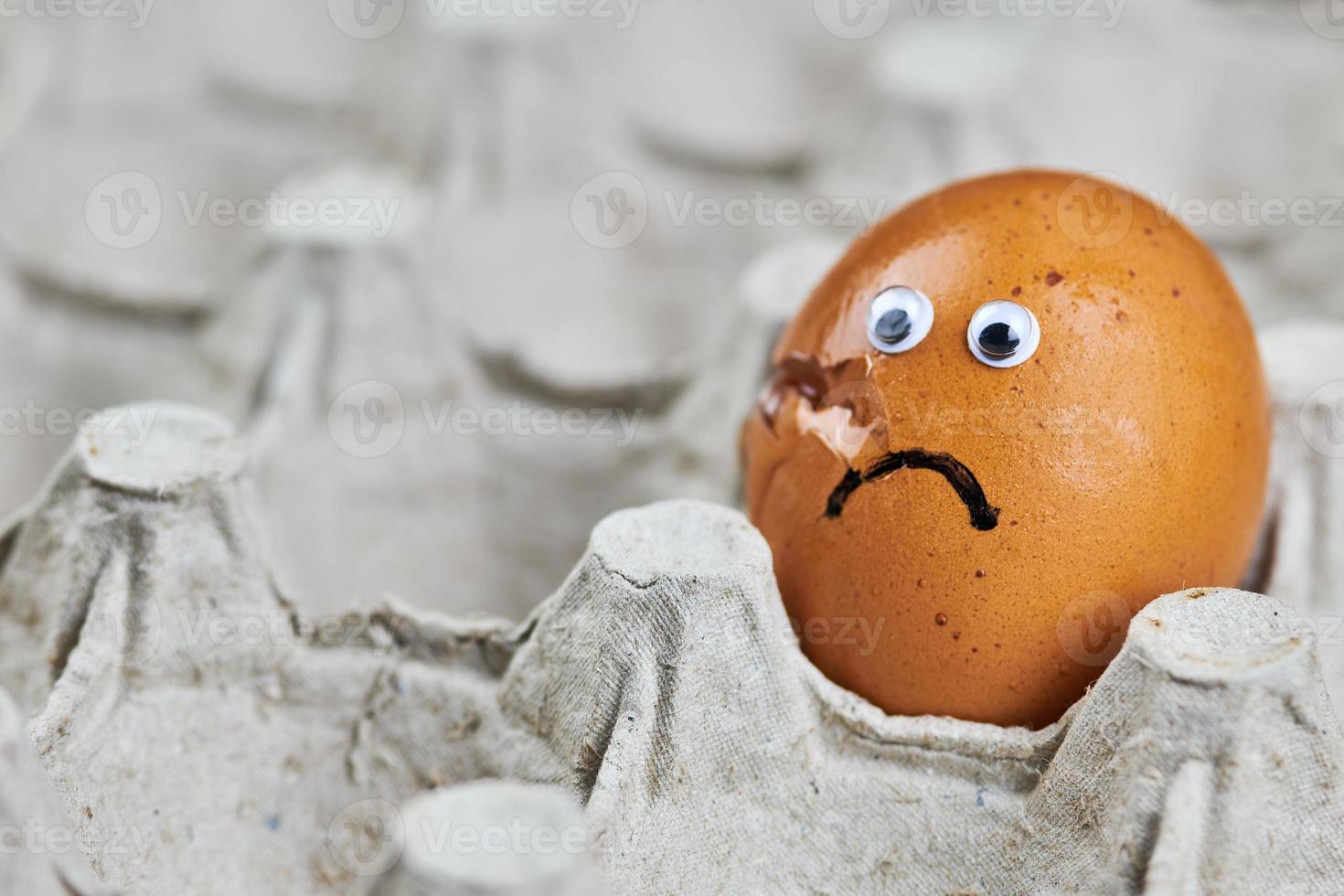 Sad cracked egg in paper egg tray photo