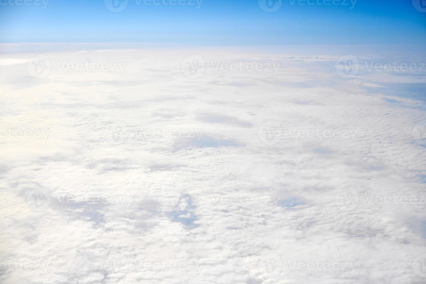 Over clouds top view from aircraft window, thick white blue clouds looks like soft foam photo