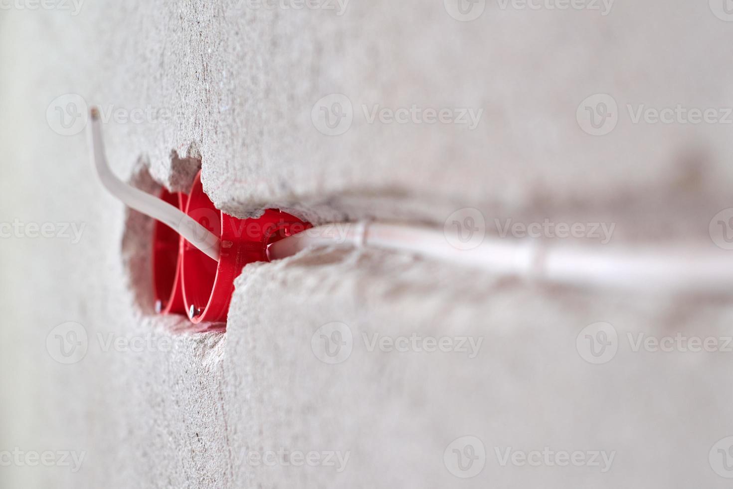 Plastic socket box and electrical wires on plastered wall photo