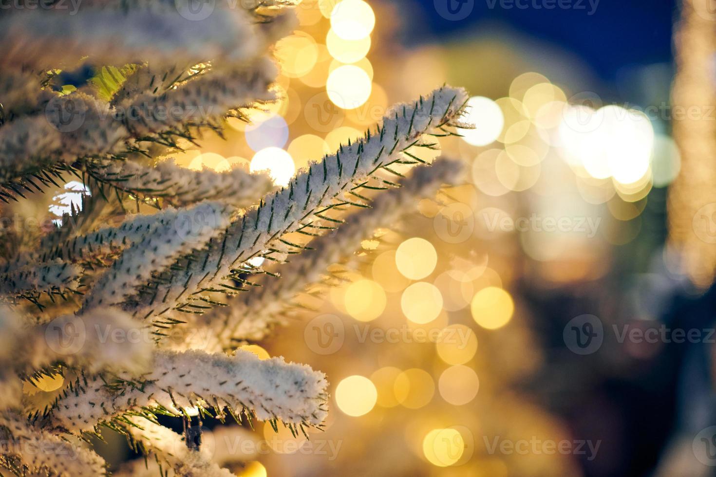 Christmas tree covered snow with yellow garlands lights and bokeh copy space with sparkled bokeh photo