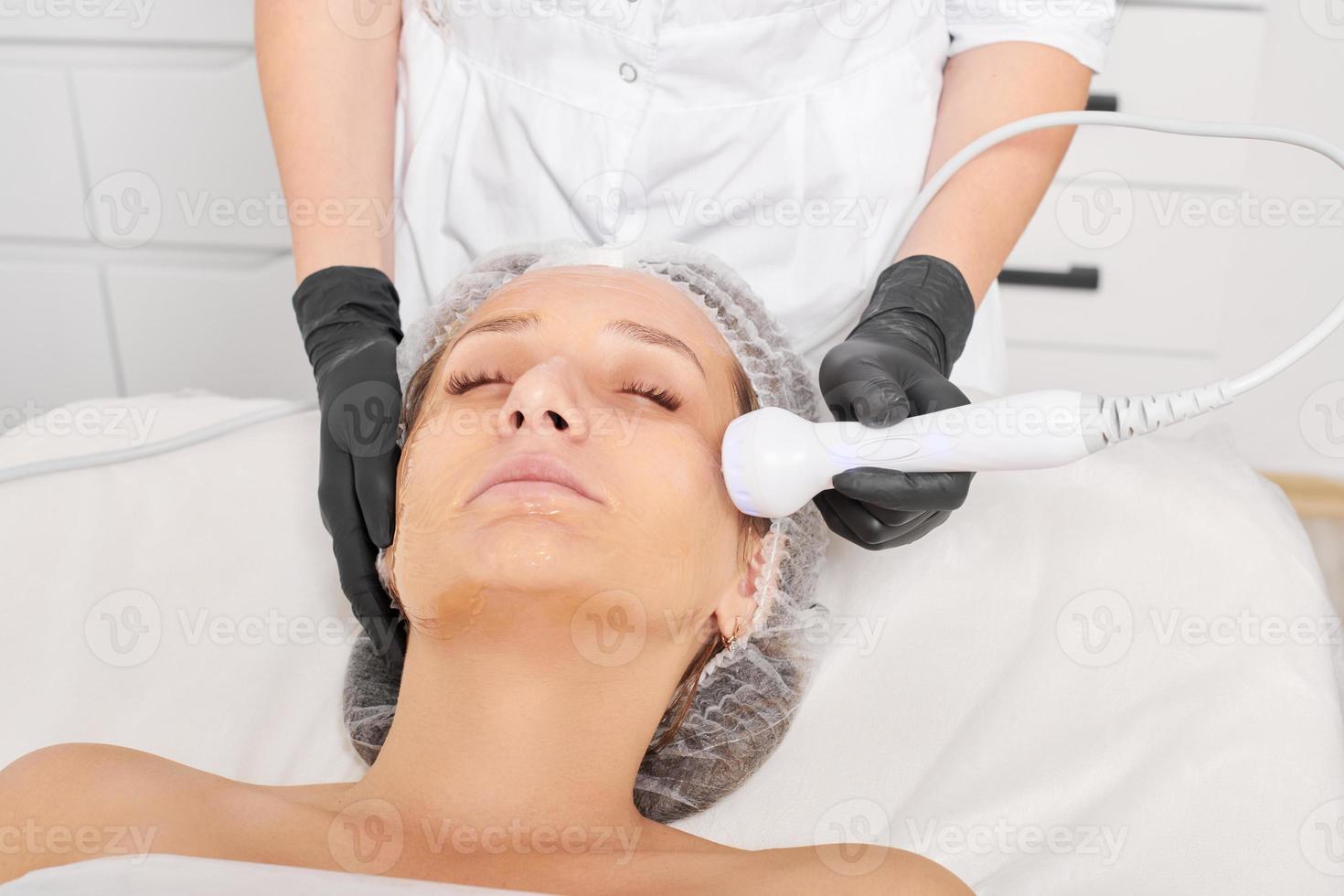 Cosmetologist makes RF lifting for rejuvenation woman face, anti aging cosmetic procedure photo