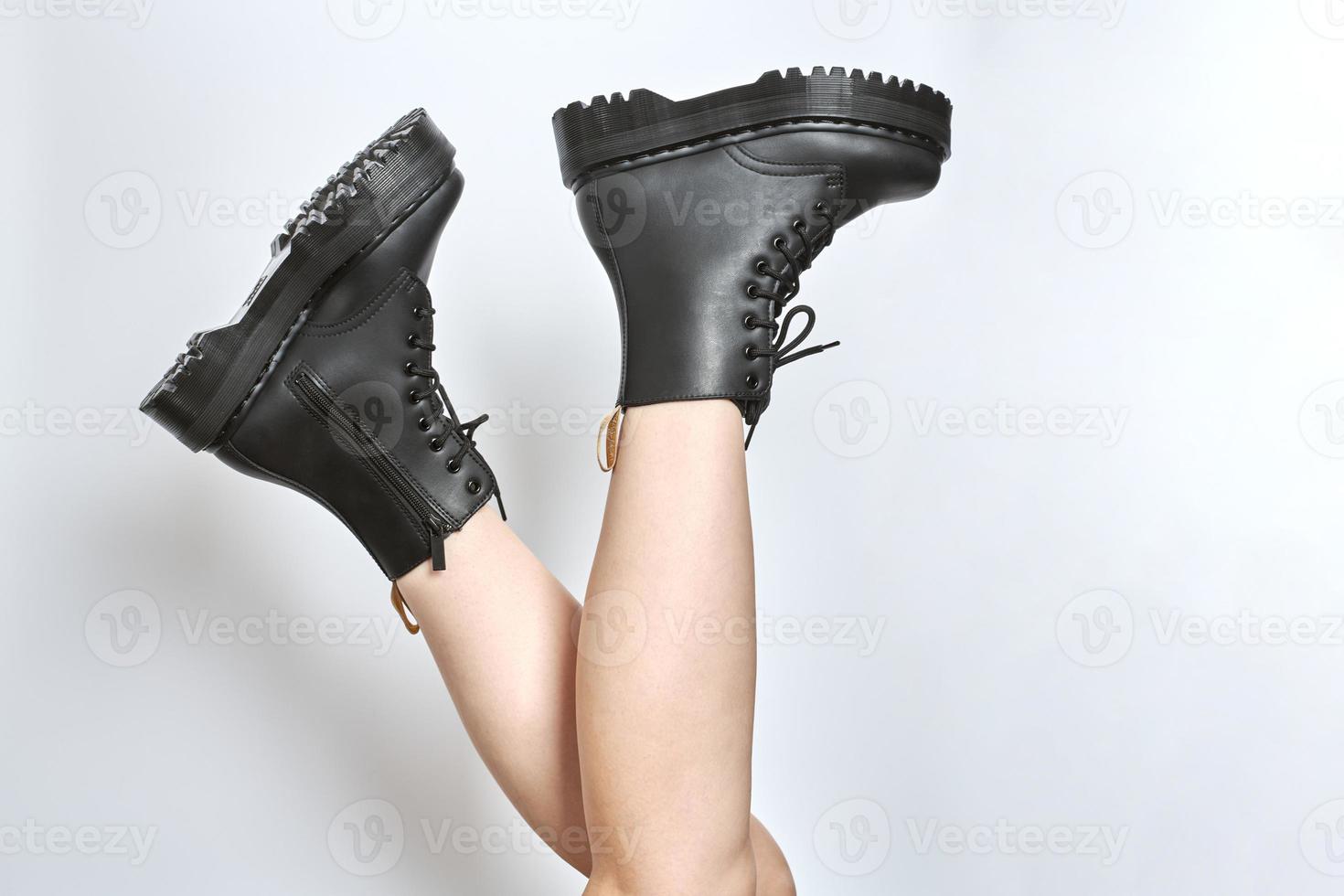 Woman legs in black combat boots on high heel platform with lug soles upside down, white background photo