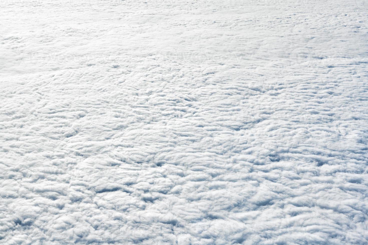 Breathtaking over clouds view from aircraft window, thick white blue clouds looks like soft foam photo