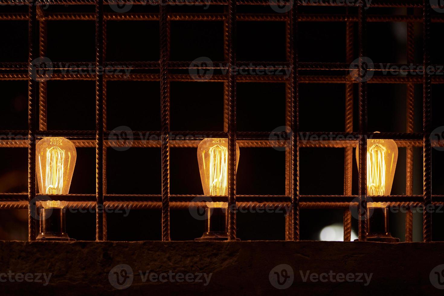 Three decorative incandescent light bulbs inside loft partition from reinforced steel bar photo