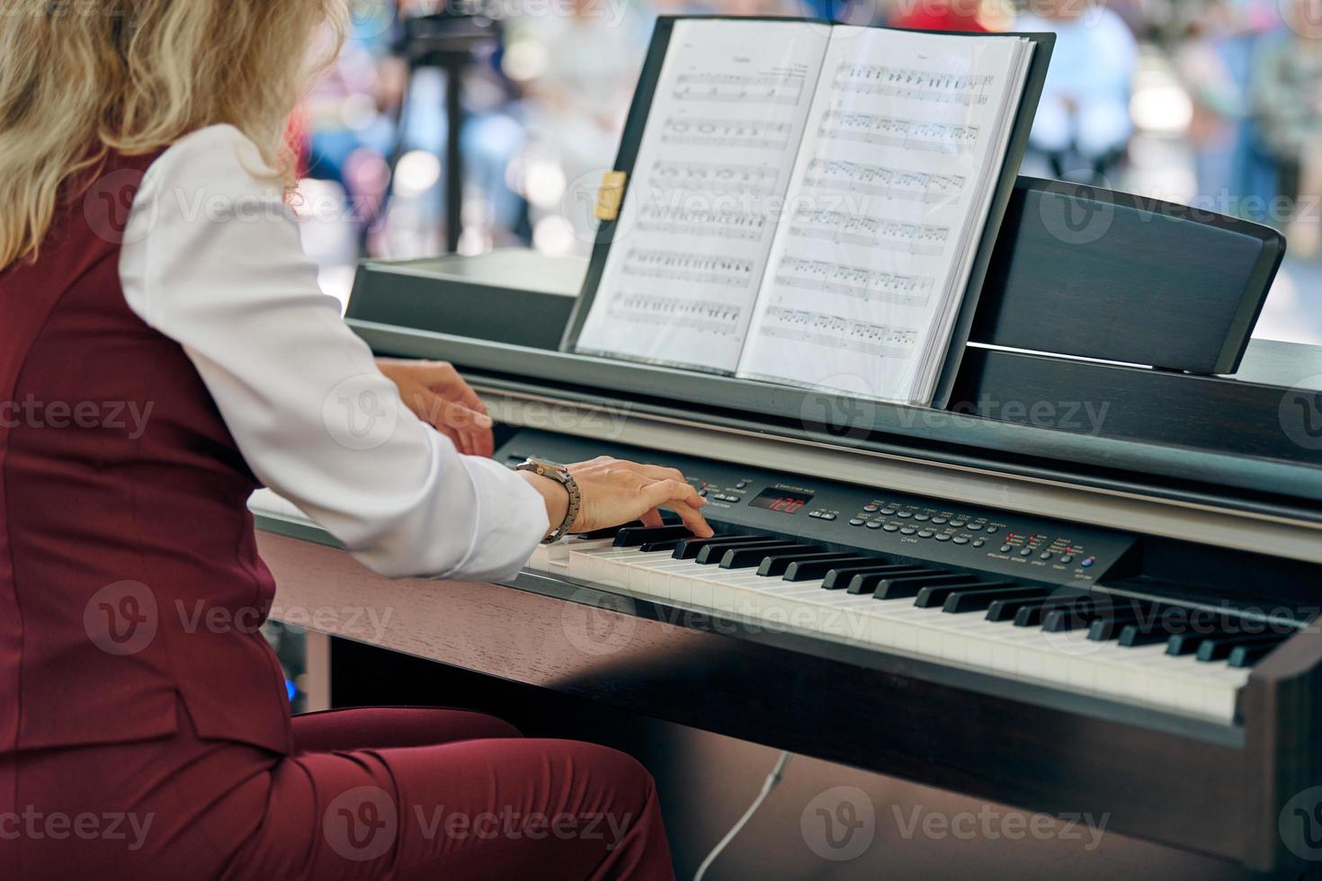 mujer obras de teatro eléctrico piano a al aire libre música actuación, adulto hembra pianista con ágil manos foto