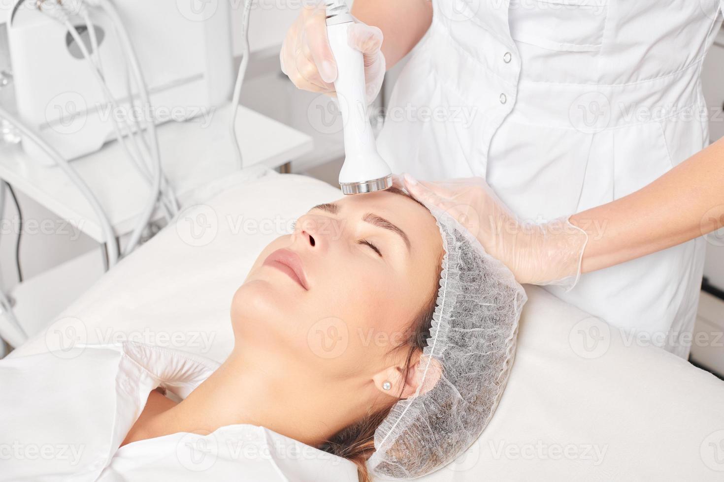 Cosmetologist makes ultrasound skin tightening for rejuvenation woman face using phonophoresis photo