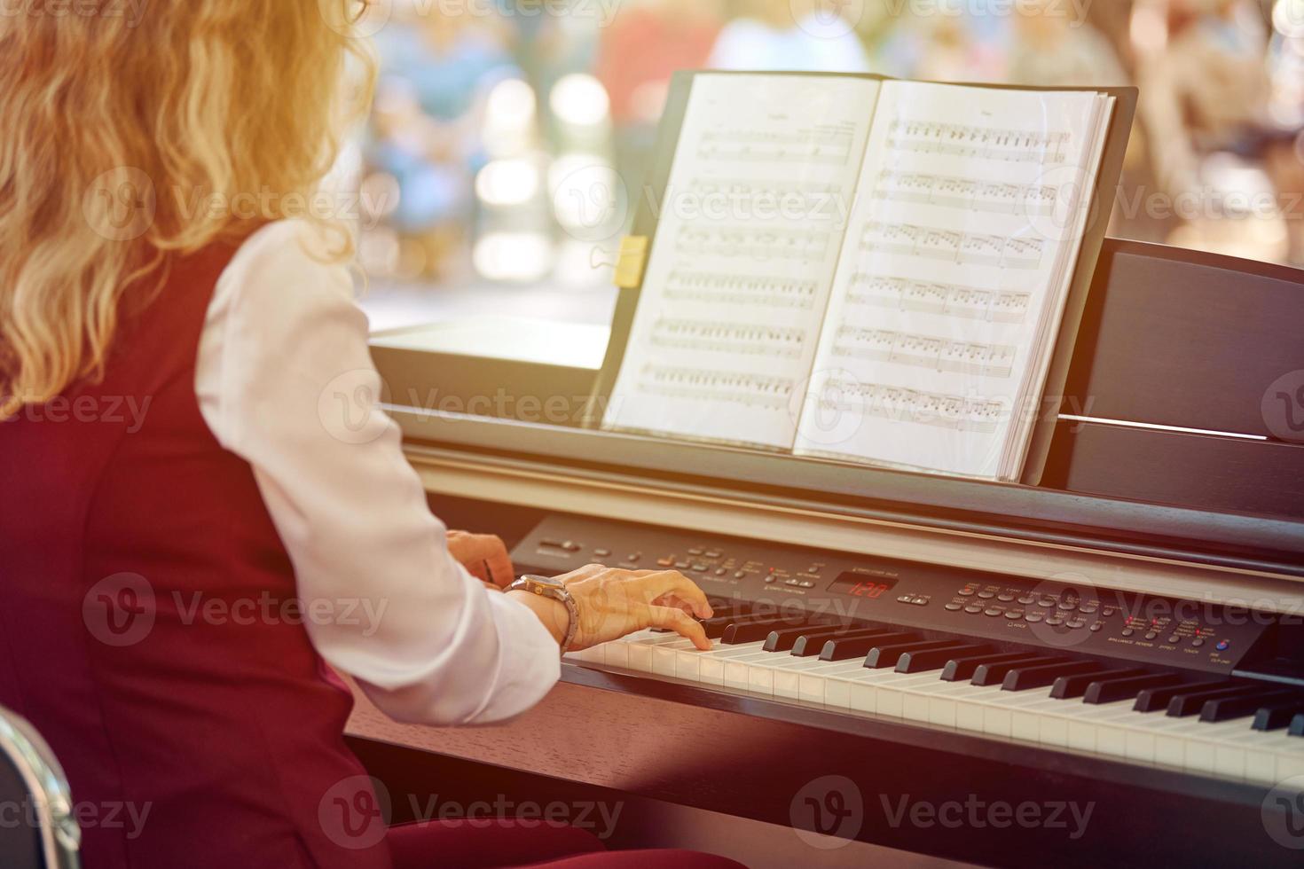 mujer obras de teatro eléctrico piano a al aire libre música actuación, adulto hembra pianista con ágil manos foto