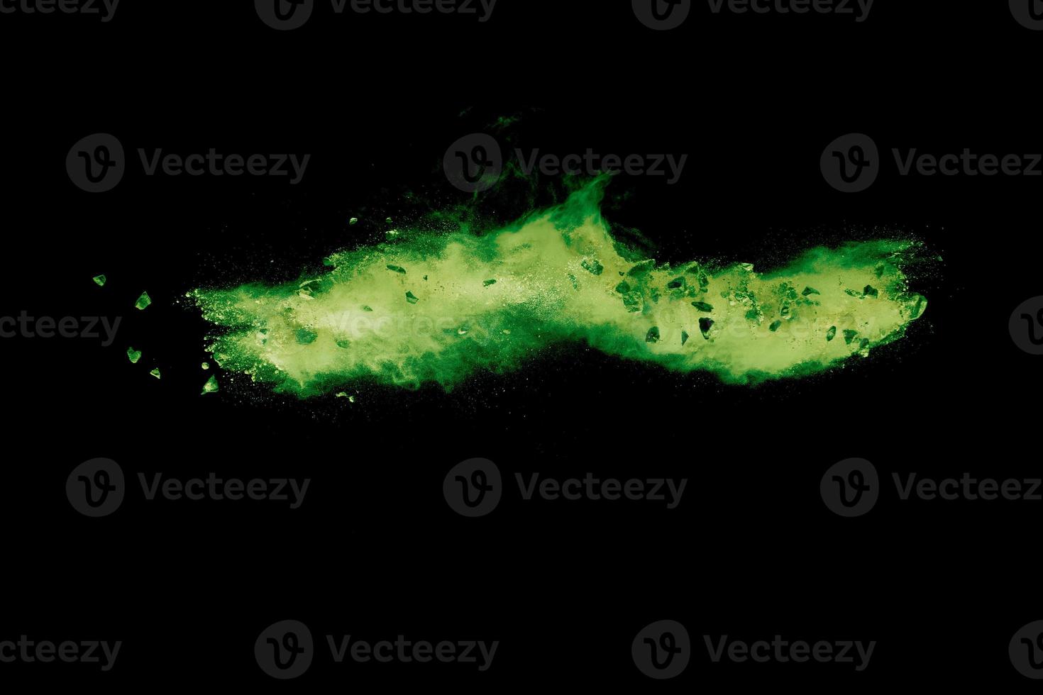 Split debris of  stone exploding with green powder against black background. photo