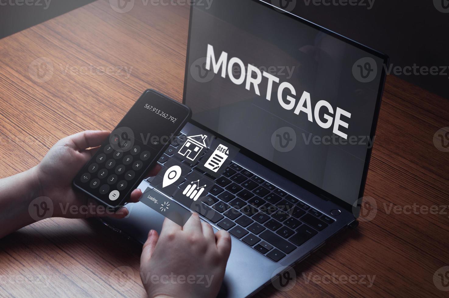 Woman using laptop and smartphone to calculate her mortgage loan. Home mortgage loan concept. Contract for hire purchase and sale a house. photo