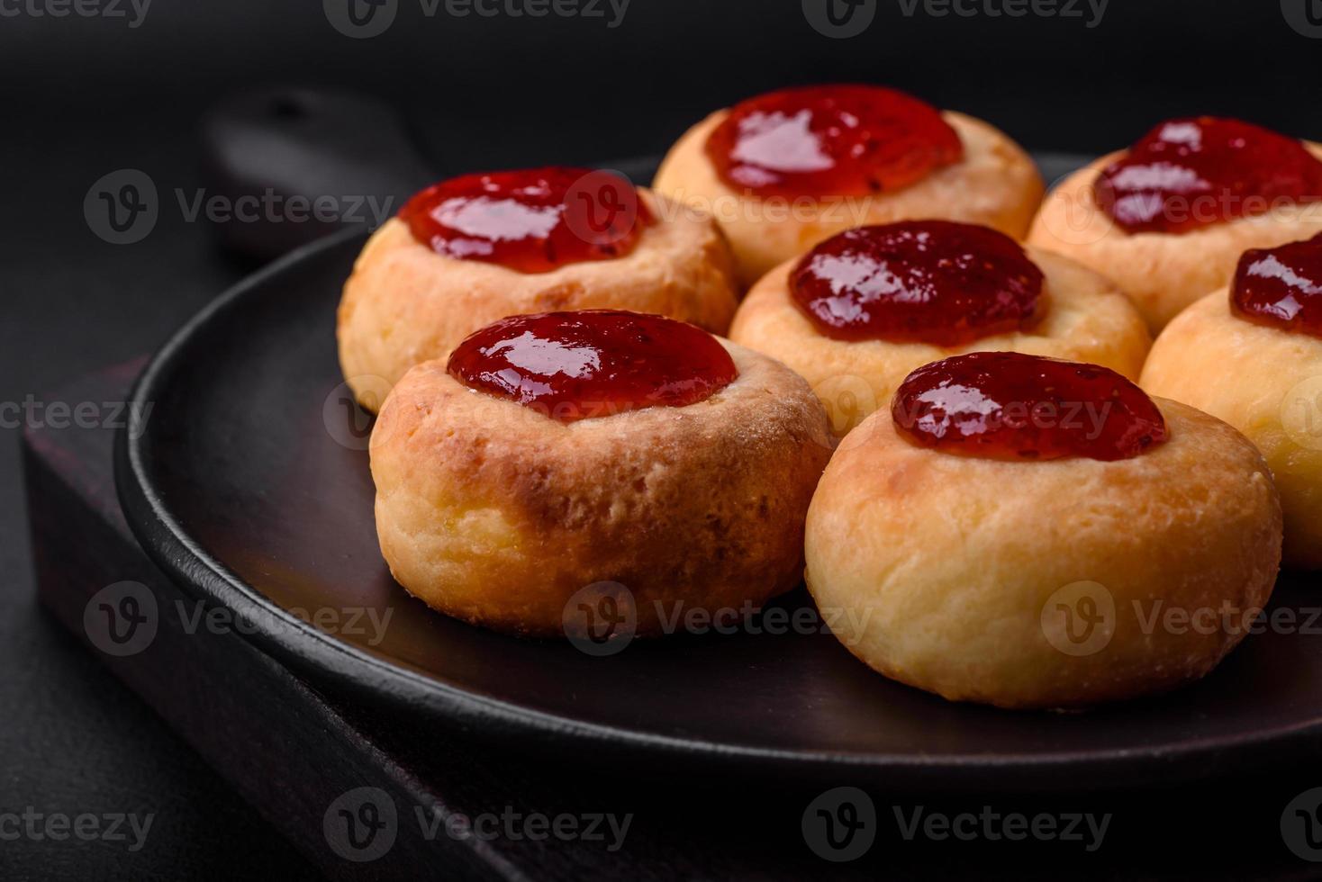 Delicious fresh cottage cheesecakes with raisins and vanilla on a black ceramic plate photo