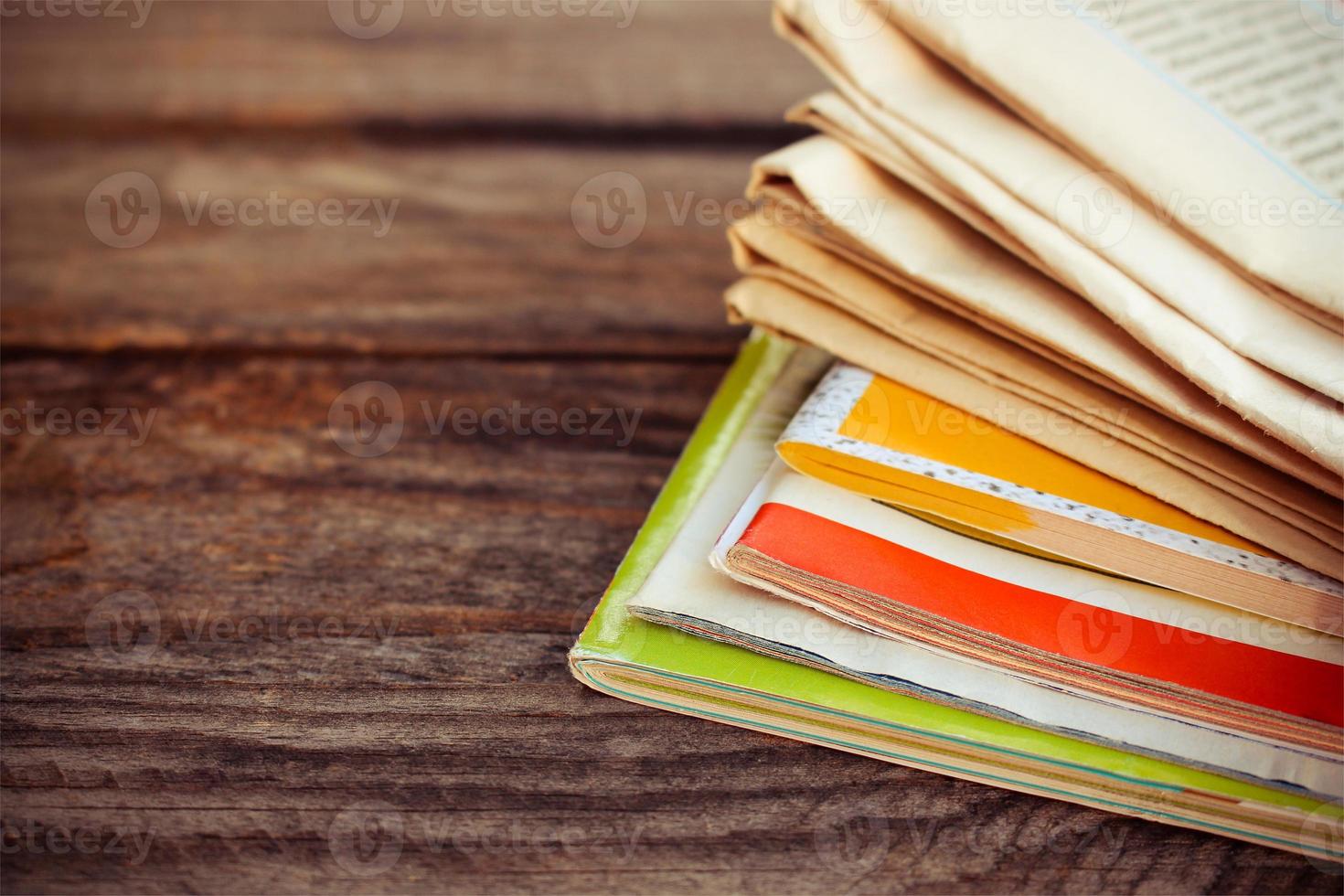 Newspapers and magazines on old wood background. Toned image. photo