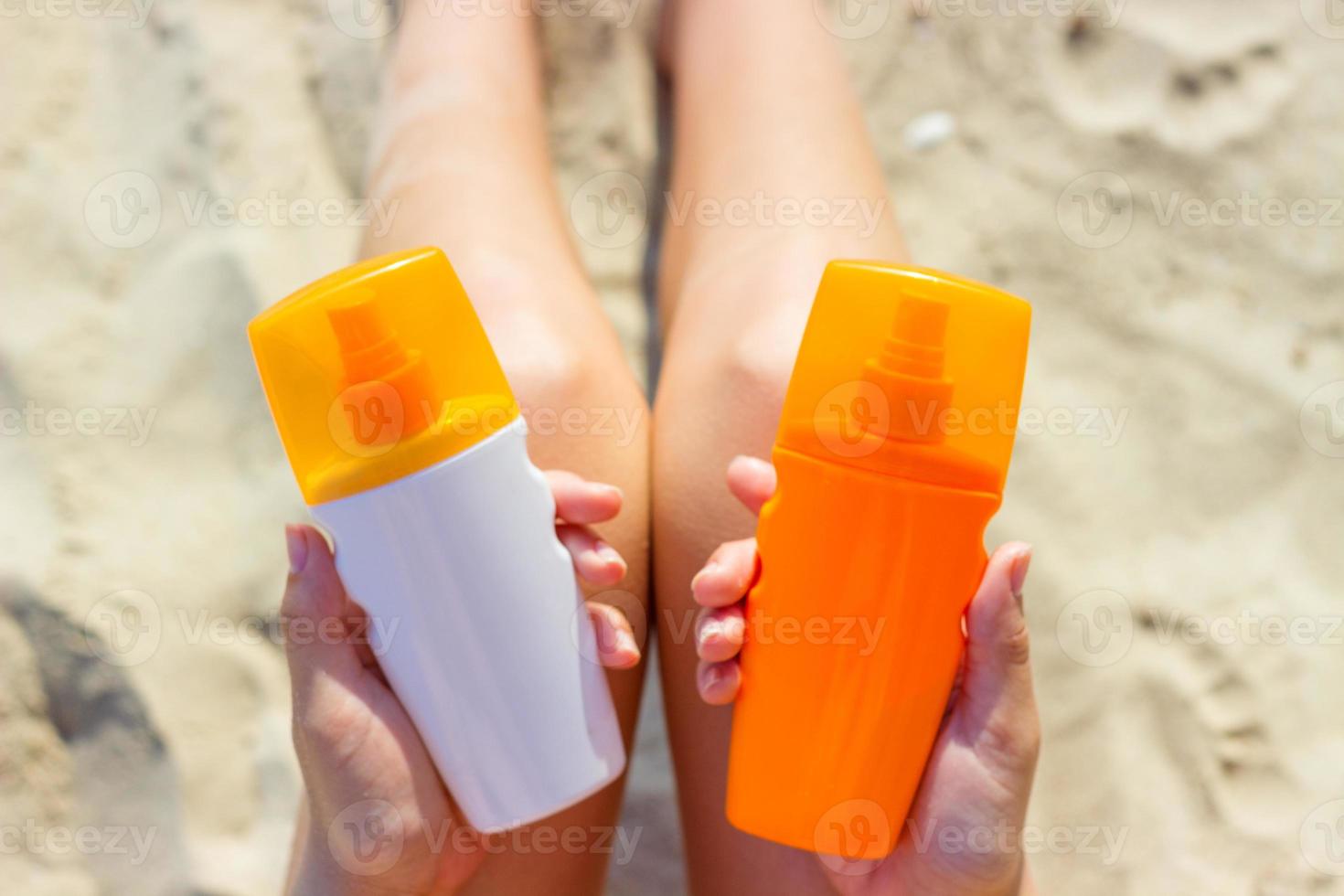 A woman holding two bottles of sunscreen in her hands. A girl chooses between two bottles of sunscreen photo