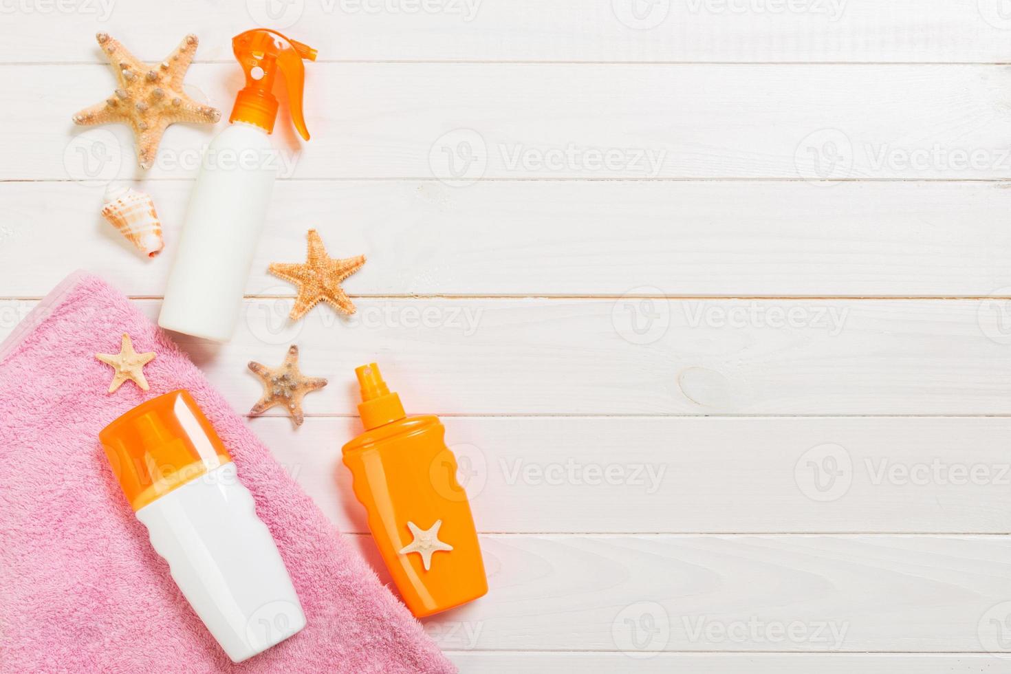 beach accessories on a white wooden background top view. Sunscreen, towel and seastar. Travel healthcare accessories top view photo