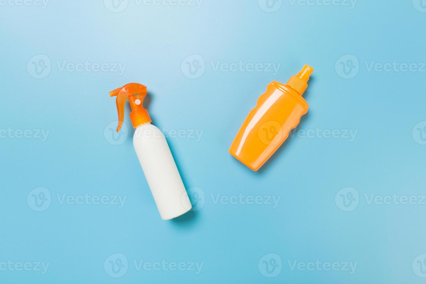 flat lay concept of summer travel vacation. Sunscreen bottle mock up on blue background top view with copy space photo